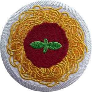 May include: A circular embroidered patch featuring a bed of yellow spaghetti noodles surrounding a central dark red tomato sauce circle topped with two small green basil leaves, all bordered by a thick white stitched edge.