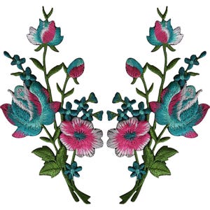 May include: A pair of symmetrical embroidered floral patches featuring vibrant teal and magenta rose-like blossoms, smaller blue accent flowers, and green stems with leaves. The intricate threadwork creates a detailed botanical design.