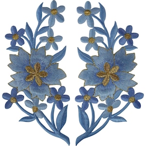 May include: A pair of symmetrical embroidered patches featuring light blue floral designs. Each patch displays a large central flower with gold-colored centers, surrounded by smaller five-petaled blue flowers and leaves, all rendered in detailed thread work.