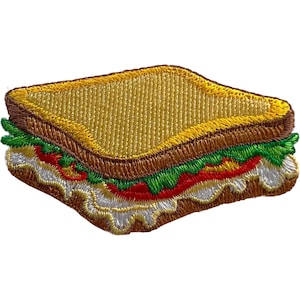 Op de afbeelding: Een geborduurde patch in de vorm van een sandwich met goudbruine broodkorsten, een gele bovenkant en zichtbare lagen van groene sla, felrode tomaat en witte kaas of mayonaise, allemaal weergegeven in gedetailleerd stikwerk.