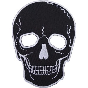 May include: An embroidered patch in the shape of a human skull. The design features a solid black background with white thread detailing that outlines the eye sockets, nasal cavity, teeth, and the cranial sutures across the forehead.