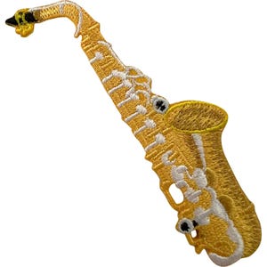Op de afbeelding: Een geborduurde patch in de vorm van een saxofoon. Het instrument is uitgevoerd in gele en gouden draadkleuren met witte details voor de kleppen en structurele elementen. Het mondstuk is zwart en geel en de beker is duidelijk zichtbaar.