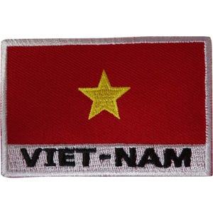 May include: A rectangular embroidered patch featuring a solid red background with a centred yellow five-pointed star. The bottom section has a white horizontal band with the black text VIET-NAM embroidered in a bold, sans-serif font style.