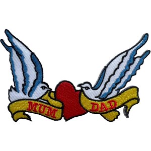 May include: An embroidered patch featuring two white birds with blue-tipped wings flying toward a central red heart. Each bird holds a yellow ribbon banner in its beak, with the word MUM written in red on the left and DAD written in red on the right.