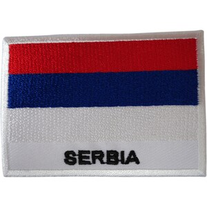 May include: A rectangular embroidered patch featuring the Serbian flag with horizontal stripes of red, blue, and white. The word SERBIA is stitched in bold black capital letters across the bottom white stripe, framed by a white stitched border.