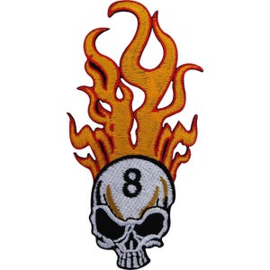 Puede incluir: Un parche bordado que muestra una calavera blanca con el número ocho en negro en la frente. La calavera está coronada por llamas estilizadas de color naranja y amarillo con bordes rojos. El diseño presenta un detallado trabajo de hilo con acentos negros.