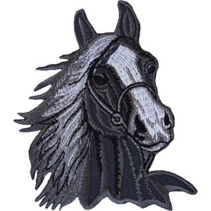 May include: An embroidered patch featuring the head and neck of a horse in shades of dark grey, black, and white. The horse has a prominent white blaze on its face, a dark grey mane, and a thin, dark grey bridle strap visible across its muzzle.