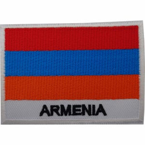 May include: A rectangular embroidered patch featuring the horizontal tricolor flag of Armenia with red, blue, and orange stripes. The bottom white stripe features the word ARMENIA stitched in bold black capital letters with a white border.