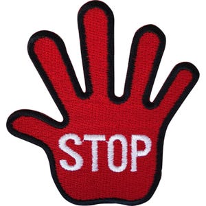 Op de afbeelding: Een rode geborduurde patch in de vorm van een open hand met gespreide vingers. De patch heeft een dikke zwarte rand en het woord STOP is in witte hoofdletters in het midden van de handpalm op een rode achtergrond geborduurd.