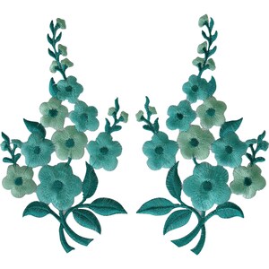 May include: Two symmetrical embroidered floral patches featuring clusters of five-petalled flowers and leaves in varying shades of teal, turquoise, and mint green. The intricate threadwork creates a botanical design with stems extending upwards.