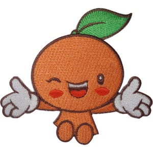 Op de afbeelding: Een geborduurde patch met een oranje cartoonfiguur met een knipogend gezicht, een brede glimlachende mond en rode wangen. Het figuur heeft een groen blaadje op het hoofd, twee kleine oranje benen en twee witte gehandschoende handen die naar de zijkanten zijn uitgestrekt.
