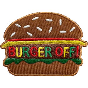 May include: A brown embroidered patch shaped like a hamburger with white sesame seeds on the bun, a yellow cheese layer, and a green lettuce layer. The text BURGER OFF! is stitched in alternating red, yellow, and green letters across the centre.