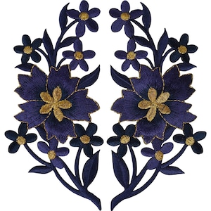 Könnte beinhalten: Ein Paar symmetrische, bestickte Blumenaufnäher mit tiefvioletten Blütenblättern und leuchtend goldenen Mitten. Jeder Aufnäher zeigt eine große zentrale Blüte, umgeben von kleineren Blüten und spitzen Blättern, gefertigt mit detaillierter Stickerei.
