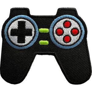 Può includere: Una toppa ricamata a forma di controller per videogiochi. La base è nera con due aree circolari bordate di azzurro. Il cerchio sinistro contiene una croce nera, mentre quello destro ha quattro punti rossi. Due piccoli rettangoli verde lime si trovano al centro.