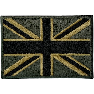 Puede incluir: Un parche rectangular bordado que presenta el diseño de la bandera Union Jack en una paleta de colores apagados. El diseño consta de una cruz central negra y franjas diagonales bordeadas por líneas beige sobre un fondo verde oliva oscuro.