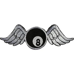 May include: An embroidered patch featuring a black circular eight ball with a white number eight in the center, flanked by two detailed silver and white wings extending outward on both sides, all outlined with a thick silver border.