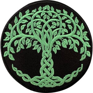 Könnte beinhalten: Ein kreisförmiger bestickter Aufnäher mit einem hellgrünen Baum, der einen geflochtenen Stamm und komplexe blättrige Zweige auf einem einfarbigen schwarzen Hintergrund zeigt. Das Design enthält ineinander verschlungene Knotenmuster.