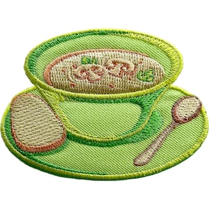 Puede incluir: Un parche bordado que muestra un cuenco verde claro lleno de sopa de champiñones beige, adornado con hierbas verdes. Una rebanada de pan y una cuchara marrón están colocadas sobre el plato verde a juego bajo el cuenco, con detalles cosidos.