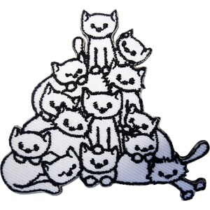May include: A white embroidered patch featuring a stack of ten cartoon cats outlined in black thread. The cats are arranged in a pyramid formation with various expressions, including closed eyes and small smiles, creating a dense cluster of feline figures.