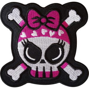 Pode incluir: Um emblema bordado apresentando um crânio branco com grandes órbitas pretas e cílios longos. O crânio usa uma bandana rosa brilhante decorada com pequenos corações brancos e um grande laço rosa no topo. Ossos cruzados brancos ficam atrás.