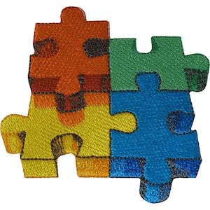 May include: An embroidered patch featuring four interlocking puzzle pieces in vibrant colours. The top left piece is orange, the bottom left is yellow, the top right is green, and the bottom right is blue. Each piece has a thick black stitched border.