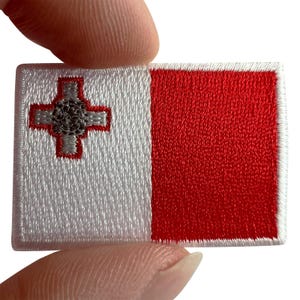 Peut inclure: Un écusson brodé rectangulaire représentant le drapeau de Malte. Le motif est divisé verticalement en deux sections égales de couleur blanche et rouge. Une croix de George grise bordée de rouge est située dans le coin supérieur gauche.