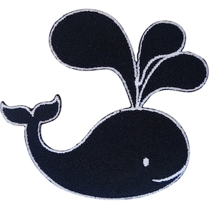 May include: A dark navy blue embroidered patch in the shape of a whale with a white stitched outline. The whale is depicted with a small white eye, a curved mouth, a tail fin, and a large water spout spraying from the top of its head.