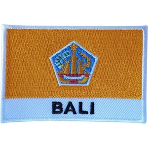 May include: A rectangular embroidered patch featuring a golden-orange background with a white border. In the center is a blue pentagonal emblem containing a golden temple structure. The word BALI is embroidered in bold black capital letters below.