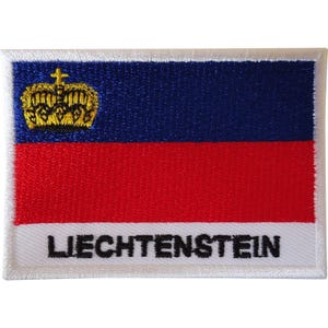 May include: A rectangular embroidered patch featuring the flag of Liechtenstein with a horizontal blue band on top and a red band on the bottom. A gold crown is positioned in the upper left corner. The word LIECHTENSTEIN is stitched in black.