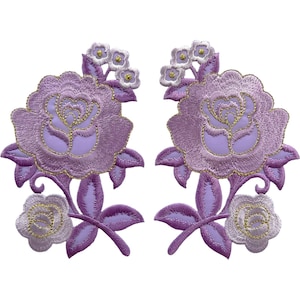 May include: Two symmetrical embroidered patches featuring lavender roses with gold thread detailing. Each patch displays a large central rose, a smaller rose at the bottom, and a cluster of tiny flowers at the top, all connected by stems and leaves.