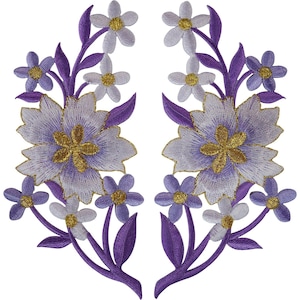 Könnte beinhalten: Zwei symmetrische, bestickte Blumenaufnäher mit großen hellvioletten Blüten mit goldenen Zentren, umgeben von kleineren hellvioletten und lavendelfarbenen Blüten sowie dunkelvioletten Blättern. Die feine Stickerei bildet ein detailliertes florales Design.