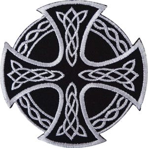 May include: A circular embroidered patch featuring a black background with a white Celtic cross design. The cross is decorated with intricate, continuous white knotwork patterns that extend into the four arms of the cross shape.