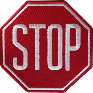 Puede incluir: Un parche bordado octogonal con un fondo rojo vibrante y un borde blanco grueso. La palabra STOP está bordada en letras mayúsculas blancas y negritas en el centro del parche, creando un diseño claro y de alto contraste.