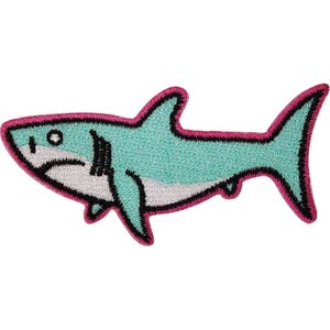 May include: An embroidered shark patch featuring a light teal body with a white underbelly. The shark is outlined in a bold, vibrant pink thread, with black stitching detailing the eye, gills, and fins to create a distinct, graphic appearance.