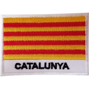 Puede incluir: Un parche rectangular bordado que presenta el diseño de la bandera de la Senyera con cuatro franjas horizontales rojas sobre un fondo amarillo. Debajo de las franjas, una banda horizontal blanca muestra la palabra CATALUNYA en letras negras.