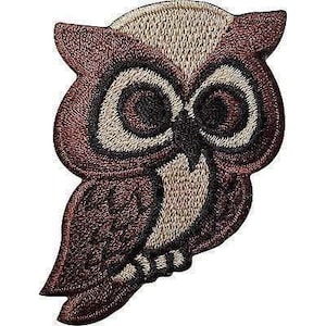 May include: An embroidered owl patch featuring shades of dark brown, light tan, and black thread. The owl has large, circular eyes with black pupils, a small pointed beak, and detailed stitching that defines the feathers on its wings and body.