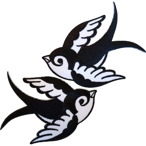 Könnte beinhalten: Zwei gestickte Schwalben-Aufnäher mit kontrastreichem Design, bestehend aus schwarzen Körpern und Flügeln, die mit weißen Federdetails akzentuiert sind. Jeder Vogel ist in einer dynamischen Flugpose mit ausgebreiteten Flügeln dargestellt.