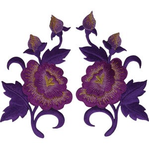 Può includere: Due toppe ricamate simmetriche raffiguranti fiori viola intenso con accenti di filo dorato al centro. Ogni toppa mostra un grande fiore in piena fioritura, un bocciolo chiuso più piccolo e diverse foglie viola con steli curvi.