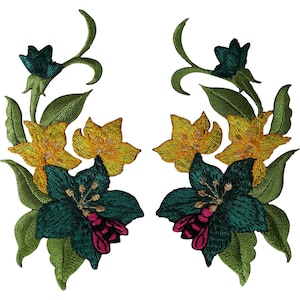 May include: Two symmetrical embroidered patches featuring floral arrangements with dark teal and bright yellow flowers, green leaves, and a small pink bee resting on the lower teal petals of each design against a plain white background.