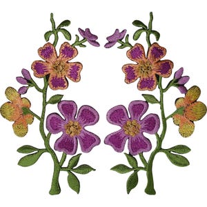 Könnte beinhalten: Zwei symmetrische, gestickte Blumenaufnäher mit violetten und orangefarbenen fünfblättrigen Blüten mit goldenen Mitten, grünen Stängeln und Blättern. Das Design umfasst kleine Knospen und zartes Blattwerk, ausgeführt in detaillierter Stickarbeit.