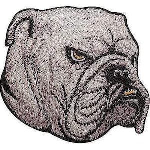Peut inclure: Un écusson brodé représentant la tête d'un bouledogue dans des tons gris et blancs. Le chien a une expression sévère avec un œil brun doré, un nez noir et une seule dent dorée visible. Le motif est entièrement bordé de fil noir.