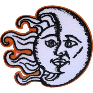 May include: An embroidered patch featuring a stylised sun and moon face design. The circular moon face is white with black embroidered facial features and outlines, while the sun rays extending from the left are orange with black borders.
