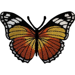 Op de afbeelding: Een geborduurde vlinderpatch met een zwart lichaam en voelsprieten. De vleugels hebben een kleurverloop van dieporanje in het midden naar goudgeel, afgewerkt met witte en zwarte geschulpte randen langs de buitenste contouren van de vleugels.