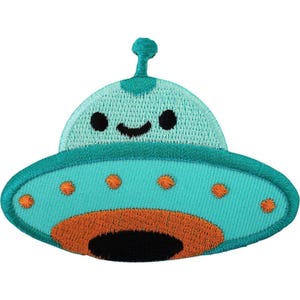 Op de afbeelding: Een geborduurde patch in de vorm van een cartoon-UFO. Het ruimteschip is lichtblauw met een donkerblauwe rand, voorzien van een kleine antenne, twee zwarte ogen en een glimlachende mond. Het heeft oranje cirkelvormige accenten en een basis.