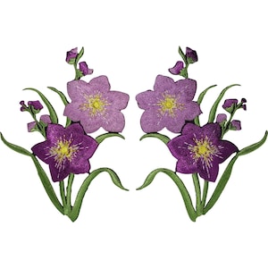 Può includere: Due toppe ricamate simmetriche raffiguranti fiori viola con centri gialli e steli verdi. Ogni toppa presenta un fiore viola scuro più grande in basso, un fiore viola chiaro sopra e piccoli boccioli su steli verdi con foglie.