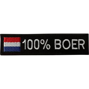 Puede incluir: Un parche rectangular negro bordado que presenta una pequeña bandera horizontal con franjas roja, blanca y azul en el lado izquierdo. A la derecha de la bandera, el texto 100% BOER está bordado en letras mayúsculas blancas sobre el fondo negro.
