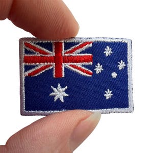 May include: A rectangular embroidered patch featuring the Australian flag design. The patch has a deep blue background with a white border, a red and white Union Jack in the upper left corner, and white embroidered stars representing the Southern Cross.