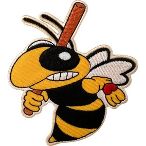 May include: An embroidered patch featuring a cartoon bee with yellow and black stripes, white wings, and a determined expression. The bee is holding a brown baseball bat over its shoulder, with a small red heart detail on its hand and black outlines.