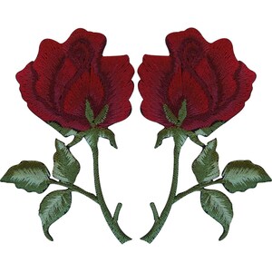 Peut inclure: Deux écussons brodés identiques en forme de rose, présentant des pétales rouge foncé avec des nuances plus sombres. Chaque rose possède une tige verte avec trois feuilles vertes distinctes. La broderie montre des points détaillés sur les pétales.