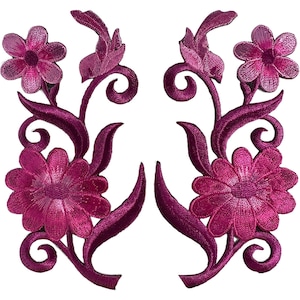 Puede incluir: Dos parches florales bordados en color magenta simétricos que presentan pétalos detallados, tallos en espiral y hojas puntiagudas. El diseño muestra una flor grande en la base y una flor más pequeña en la parte superior, en hilo rosa intenso.